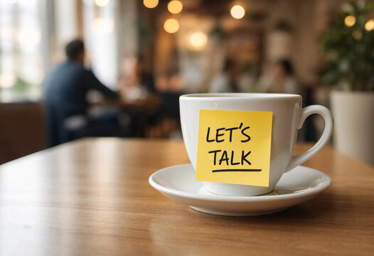 Coffee cup on a table with a yellow sticky note saying lets talk