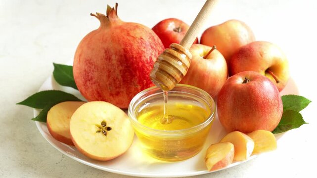 Happy Rosh Hashanah. Jewish New Year holiday concept. Honey dipper in a bowl with honey, next to apples, shofar horn and pomegranates.