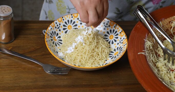 Garnishing traditional Moroccan Seffa vermicelli with icing sugar and cinnamon