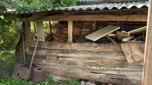 An abandoned village barn filled with old planks and scattered debris, rustic architecture, rural decay, forgotten countryside, weathered structure.