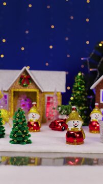 A yellow car drives past the houses and snowmen