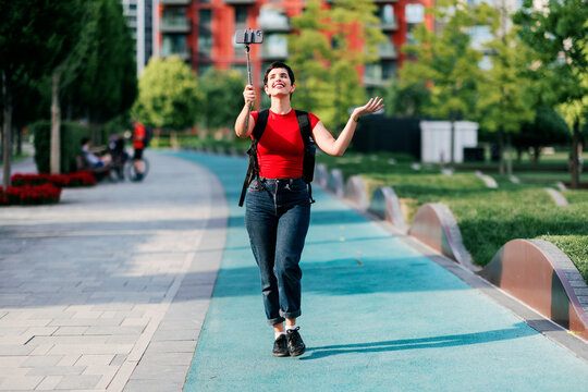 Woman vlogging outdoors walking using selfie stick