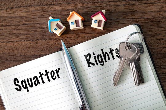 Squatter Rights text on notebook with keys and toy houses on wooden desk, real estate and property law concept