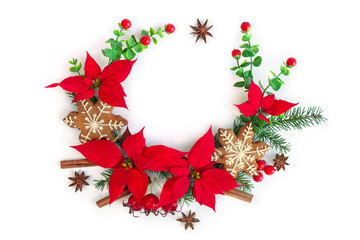 Fototapeta premium Christmas decoration with red poinsettia, gingerbread cookie, and winter spices on white background with space for text. Flat lay, top view