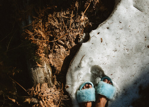 woman's feet in slippers on a patch of snow