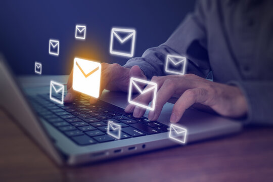 Person typing on laptop with glowing email envelope icons flying, digital communication and email marketing concept