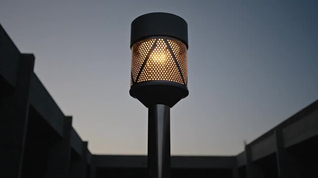 Low angle shot of modern illuminated outdoor lamp against a dusk sky and architectural elements