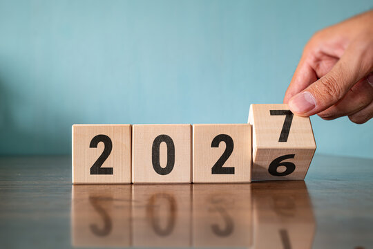 Hand turning wooden block cube changing year from 2026 to 2027, new year planning and business goals concept