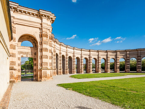 Palazzo Te creating a curved Renaissance colonnade in Mantova, Italy, offering a view of historical architecture and beautiful surrounding gardens under a clear sky