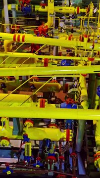 Intricate piping with colorful fittings. Lively factory piping system with vibrant components. Bustling industrial interior showcasing dense network of colorful pipes and mechanical arrangements