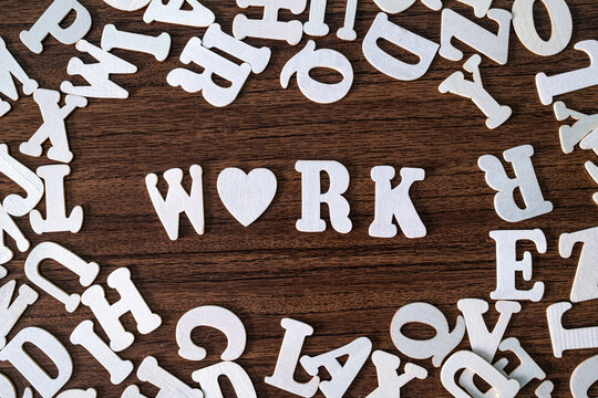 WORK word with heart symbol spelled with letter tiles on scattered letters wooden background, employment and career concept