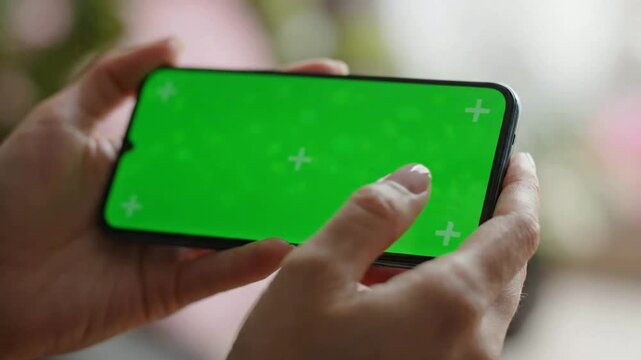Person holding smartphone with green screen chroma key for app interface mockup and digital marketing creation
