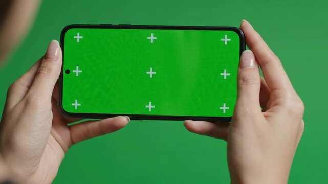 Person holding smartphone with green screen chroma key display for easy compositing and app mockup presentation