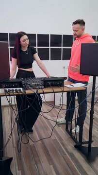 Music lesson with two DJs discussing sound mixing approaches at studio console. DJs, music lesson, studio, discussion, mixing