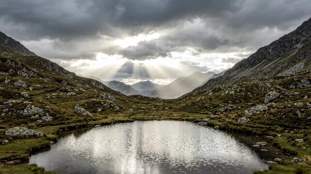 Mountain landscape with small alpine lake and dramatic sunbeams through clouds