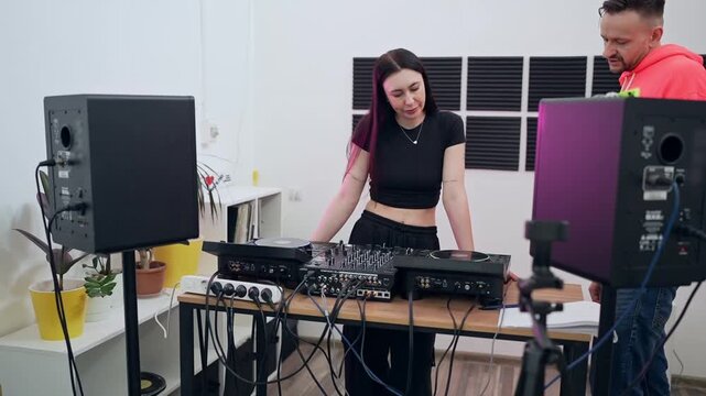 DJs collaborating in large white studio mixing music on DJ controllers and turntables. DJ, collaboration, studio, music, controllers, turntables