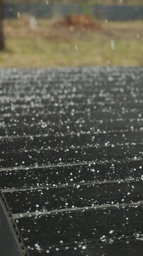 Vertical video. Snowflakes fall across a rain-darkened terrace during the season's first snowfall.
