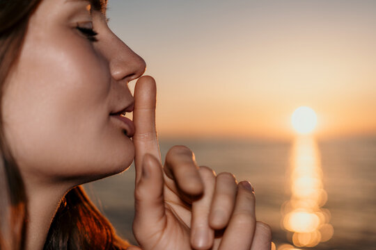 Silence woman sunset showing shh gesture with finger on lips at the beach during golden hour sunset with copy space