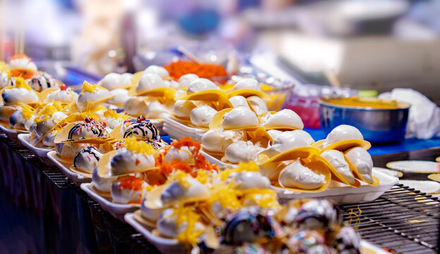 Traditional Thai crispy pancakes Khanom Buang displayed at a vibrant Asian night market