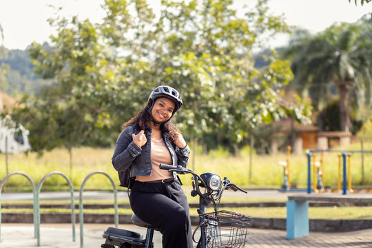 Confident young Black woman adjusting her backpack while sitting on her electric bicycle, representing an active, sustainable lifestyle.