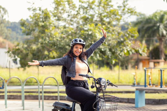 Joyful young Black woman celebrating freedom on her electric bicycle, representing an active and sustainable lifestyle.