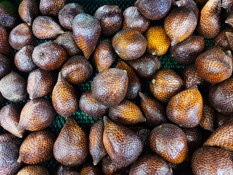 Fresh salak fruits arranged in a tray for sale, showcasing their distinctive scaly brown skin, natural variation in color, and abundant tropical produce at a local market.