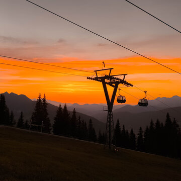 Summer sunset or sundowner view with silhouettes of a cable car mast and gondulas at Mount Asitz, Leogang, Zell am See, Pinzgau, Salzburg, Austria