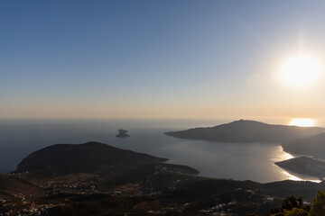Fototapeta premium Golden sunset bathes a tranquil coastline and calm sea, with silhouetted hills and distant islets creating a peaceful, expansive horizon ideal for travel, nature, and landscape photography. Turkey