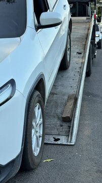 SUV slowly drives up a flatbed tow truck during a roadside recovery operation. Professional vehicle transport, towing service and automobile loading in progress.