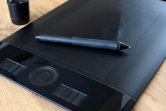 Digital stylus rest on a black graphics tablet for digital drawing. Digital illustration process concept.