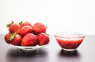 Small plate of red raspberries and a bowl of raspberry puree, colorful fruit display, fresh berry assortment, vibrant produce presentation, culinary setup © ketrin