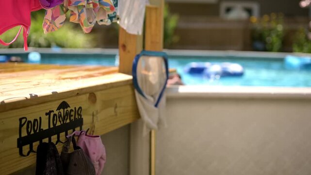 4K video of organized poolside towels, children&rsquo;s flotation aids, and swimming gear beside a backyard pool