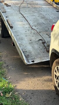 Tow truck flatbed slowly moves into position for vehicle loading. Roadside towing process, transportation service and car recovery preparation.