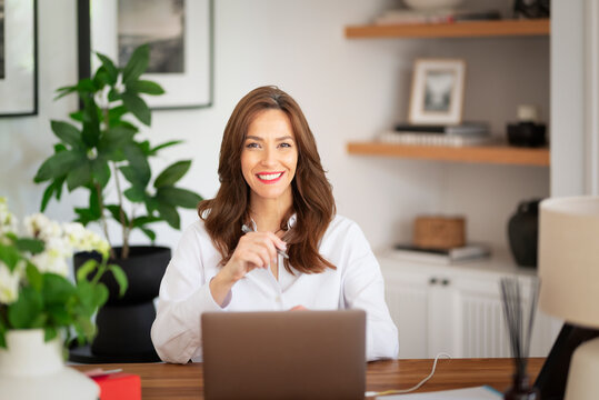 Confident middle-aged woman using laptop when working from home