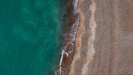 Top-down aerial view of Eastbourne's pebble beach, emerald shoreline and coastal road, revealing striking natural patterns and urban geometry along the East Sussex coast, England. © Francois Quartiers