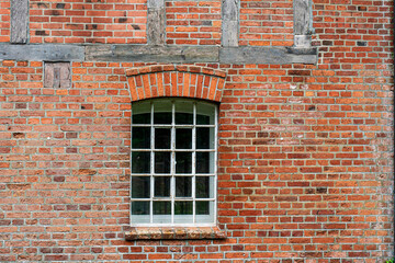 Fototapeta premium Old wooden window on red brick wall facade