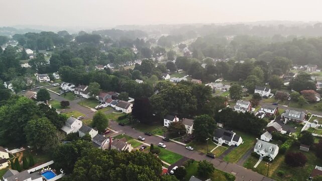 Aerial view of a Connecticut suburb covered in wildfire smoke haze, showing homes, roads, and trees under poor air quality, highlighting climate change, environmental risks, and wildfire impacts.