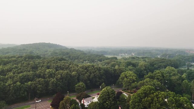 Aerial view of wildfire smoke spreading over a suburban forest in the USA, showing air pollution, climate change, environmental hazard, and wildfire impact.
