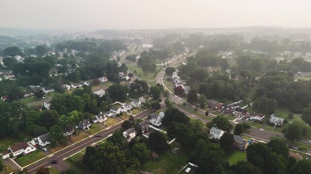 Aerial view of a Connecticut suburb covered in wildfire smoke haze, showing homes, roads and trees under poor air quality, representing climate impact.
