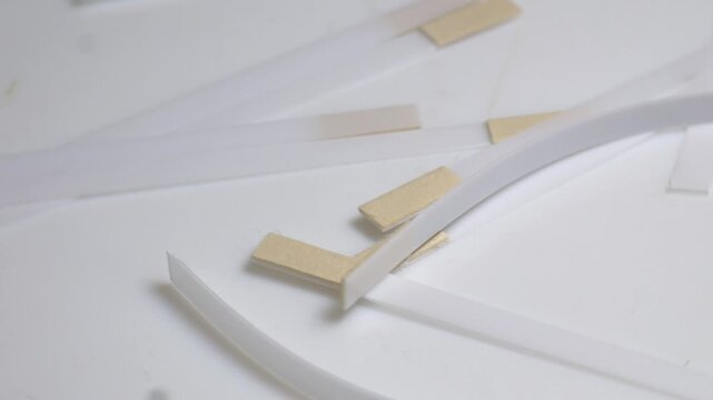 Close-up of white medical test strips with indicator pads rotating on a turntable under bright studio lighting.