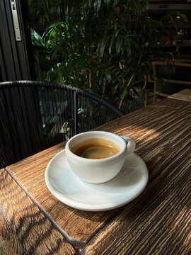 Fresh Espresso Coffee in White Cup on Wooden Table in Cozy Cafe