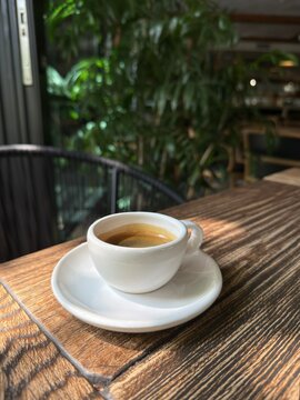 Fresh Espresso Coffee in White Cup on Wooden Table in Cozy Cafe
