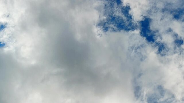 Thick storm clouds with patches of bright blue sky creating a dramatic natural cloudscape. Perfect for weather, climate, nature and background projects  