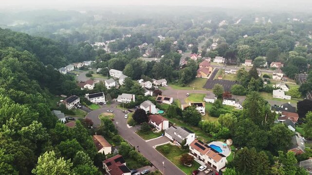 Aerial view of Connecticut suburban neighborhood covered in wildfire smoke haze, with homes, roads, and trees beneath poor air quality. Climate change, environmental impact, and air pollution.