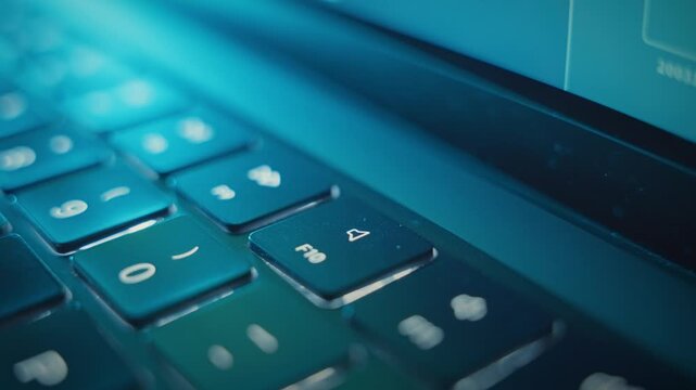 Close up on finger pressing Mute key with small illuminated icon on laptop. Dark office or control room as finger clicks to mute sound and volume from computer. Lowering audio levels in music studio