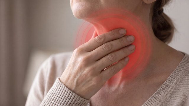 Woman touching throat in pain with area highlighted in red representing sore throat discomfort