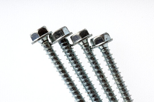 Close-up of metal hex bolts. The bolts are shiny and have a threaded stem, located on a white background.