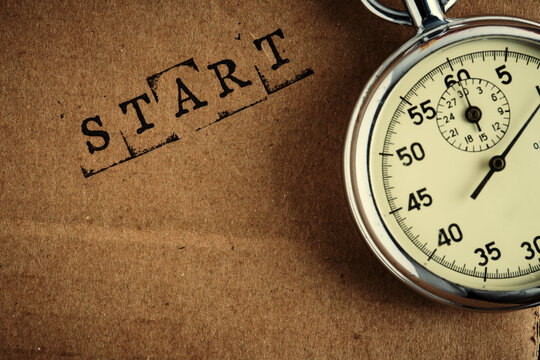 Close up shot mechanical stopwatch and stamped word START on craft paper texture background.