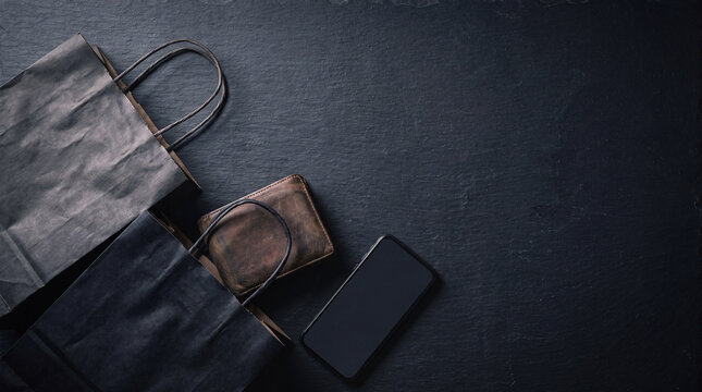 Shopping bags with a leather wallet and smartphone on slate