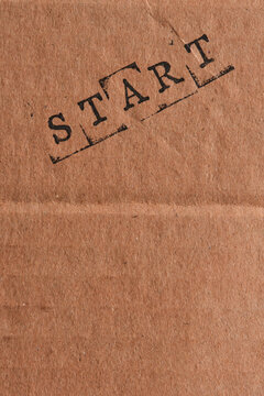 Vertical composition showing word START stamped diagonally on brown cardboard textured background.